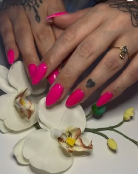 Leuchtend pinke Maniküre mit einer weissen Orchidee.