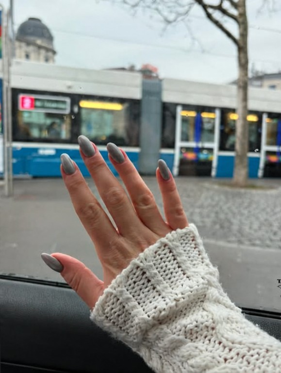 Graue Maniküre vor einer Strassenbahn in der Stadt.