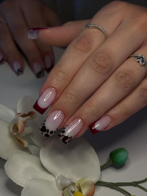 Zartrosa French-Maniküre mit bordeauxroten Spitzen und gepunktetem Nageldesign.